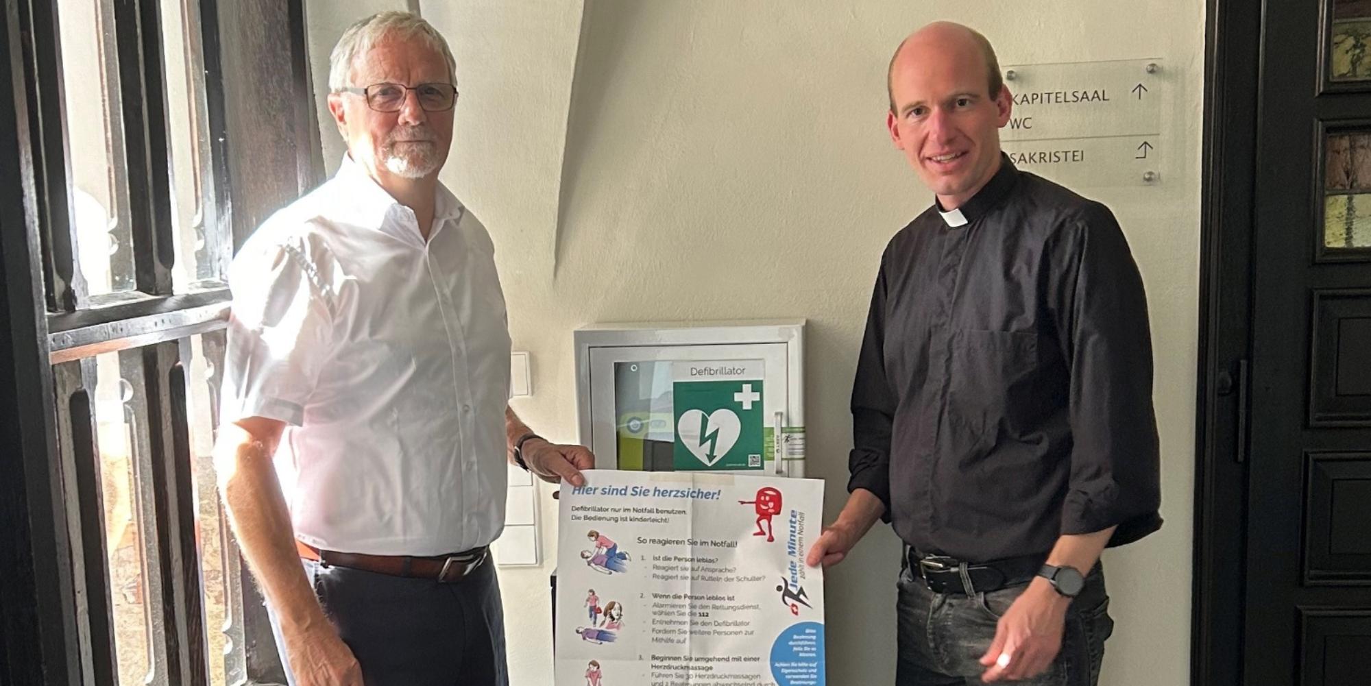 Ulrich Lipperheide, Vorsitzender des Münster-Bauvereins,  und Kaplan Dr. Chrisitan Jasper bei der Vorstellung des neuen Defibrillators